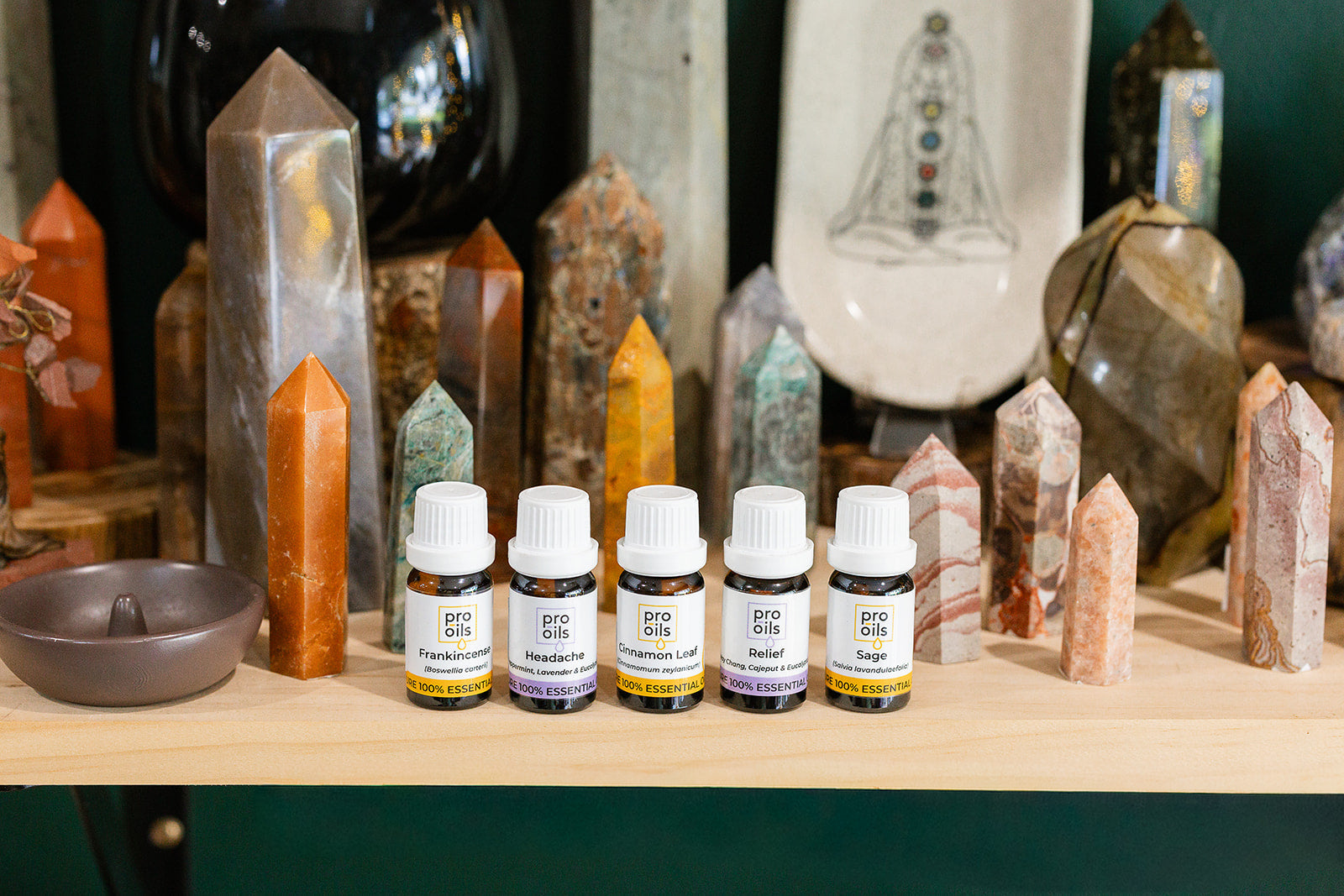Shelf with a row of essential oils in front of crystal towers in all different colours