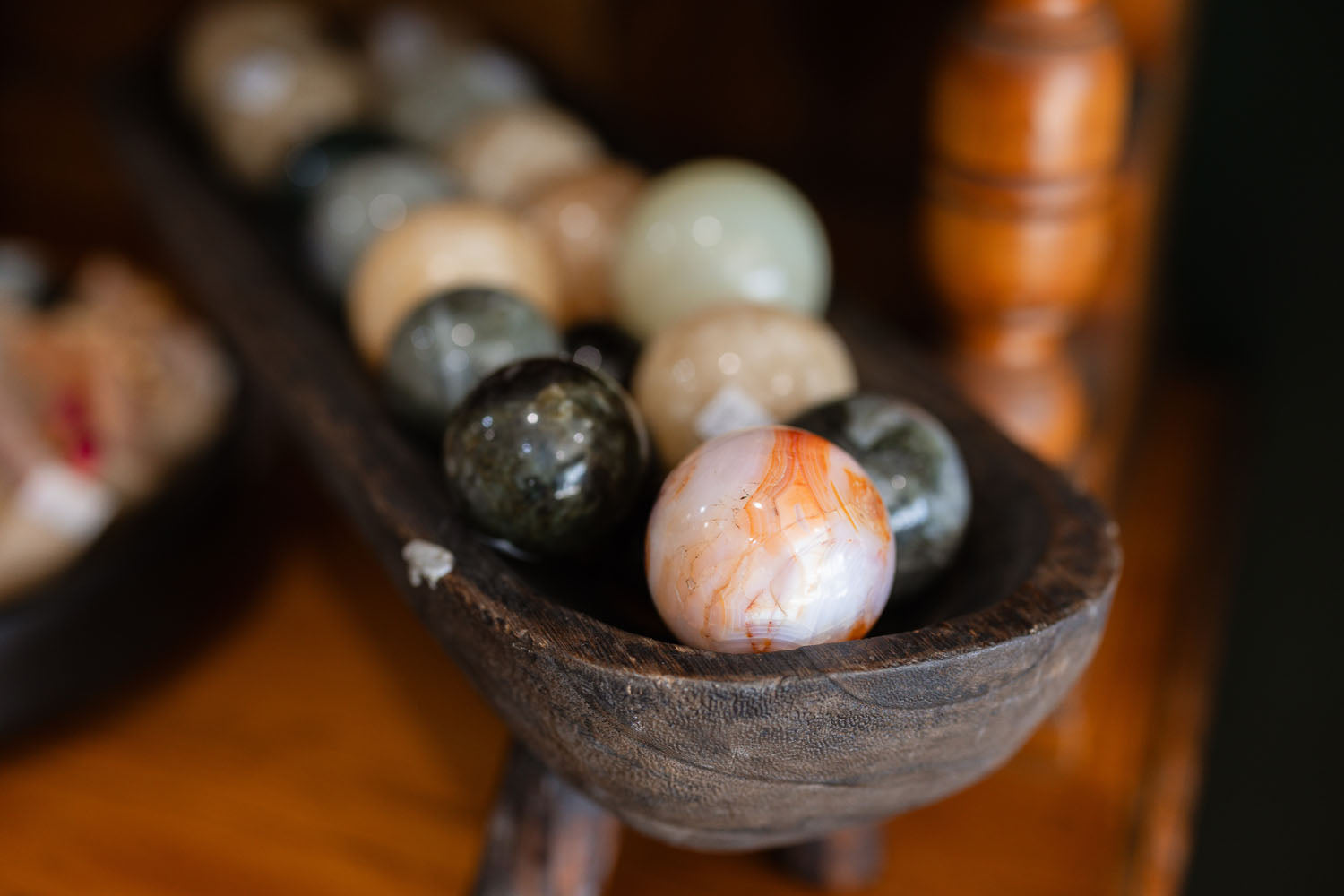Wooden bowl holding a selection of stone spheres on a shelf 