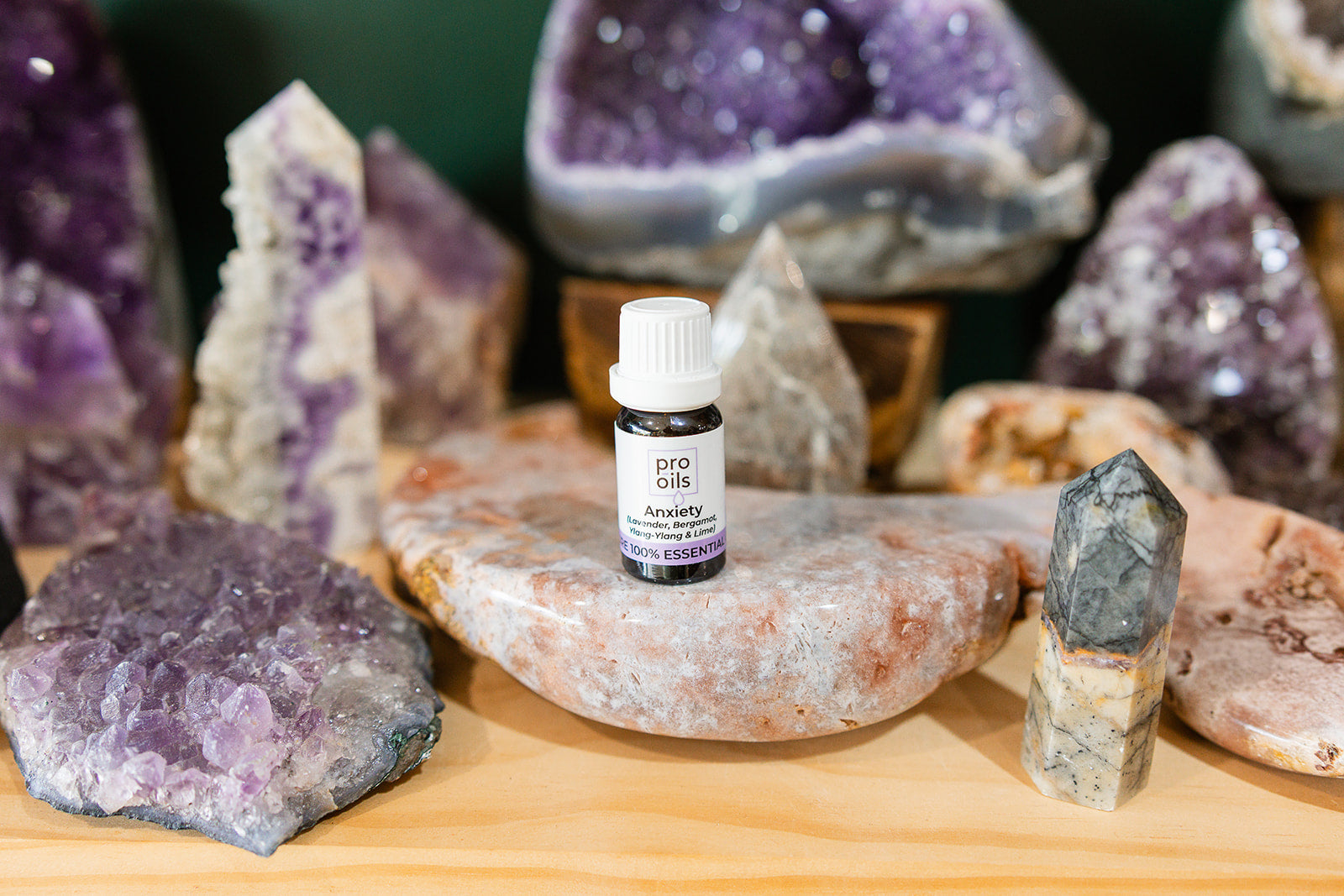 Small bottle of Anxiety Essential Oil Blend on a wooden surface with crystals in the background