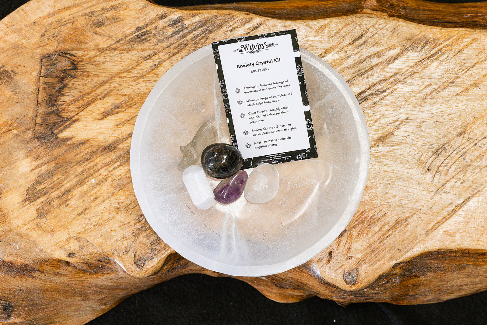Packaged product labeled ‘Anxiety Tumble Kit' by 'Witchy Nook' on a wooden surface in the background with products displayed in a bowl.