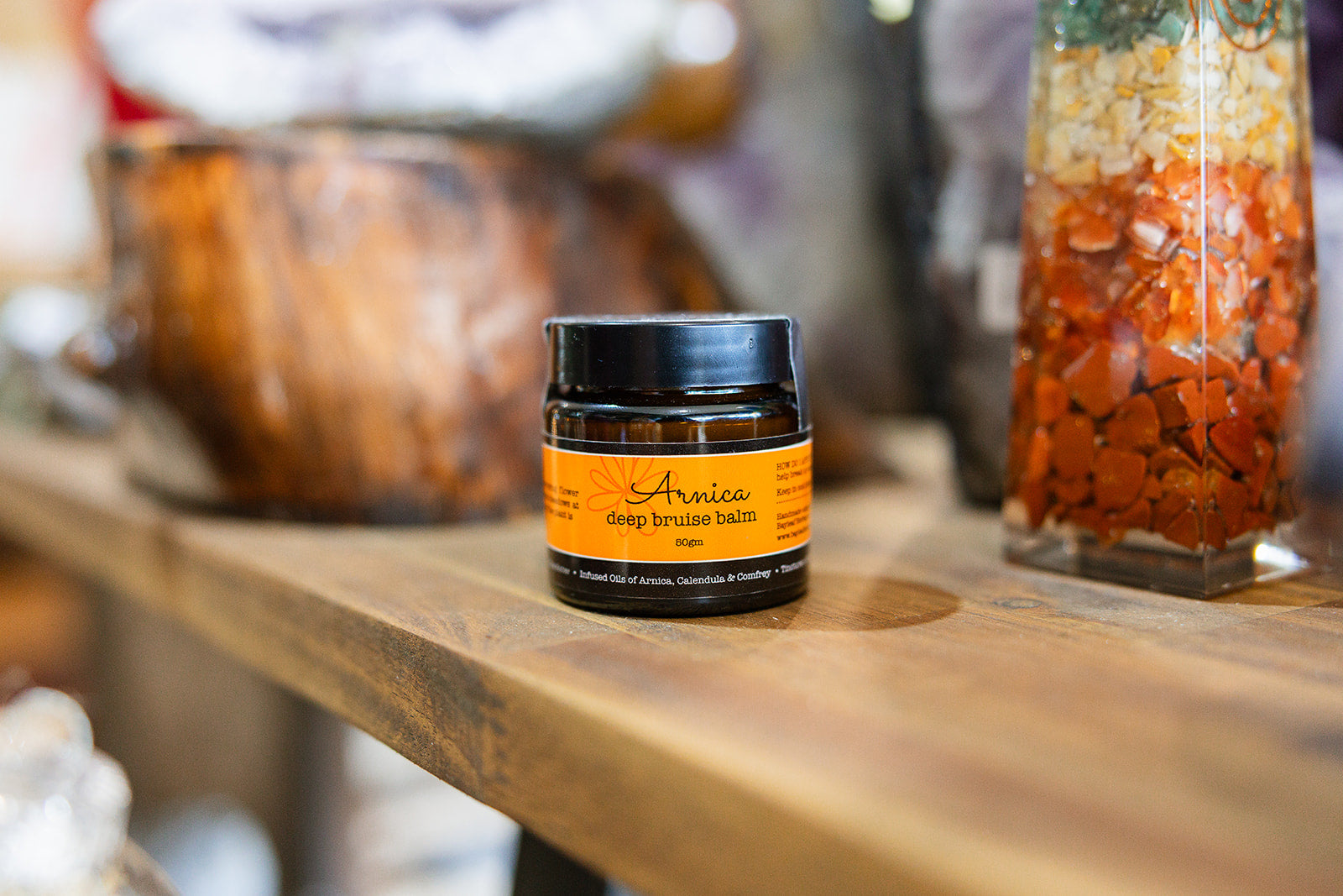 Balms and rubs Arnica Deep Bruise Relief displayed on a wooden surface with a blurred background.