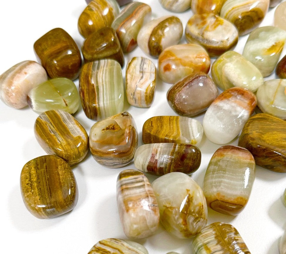 The image displays a collection of polished Banded Onyx tumbled stones on arranged on a white background