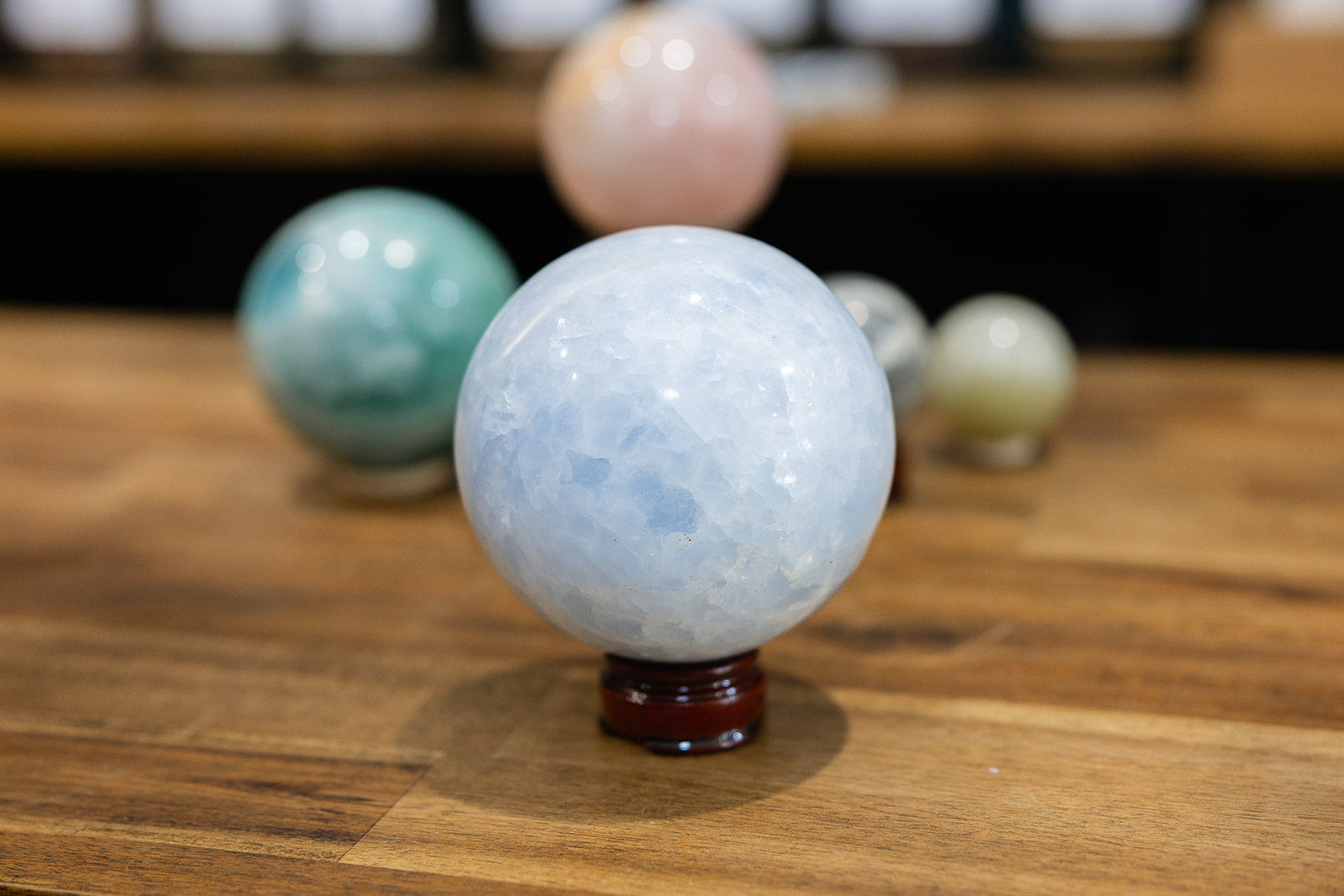 Blue calcite sphere with Set of colorful crystal balls on a wooden surface