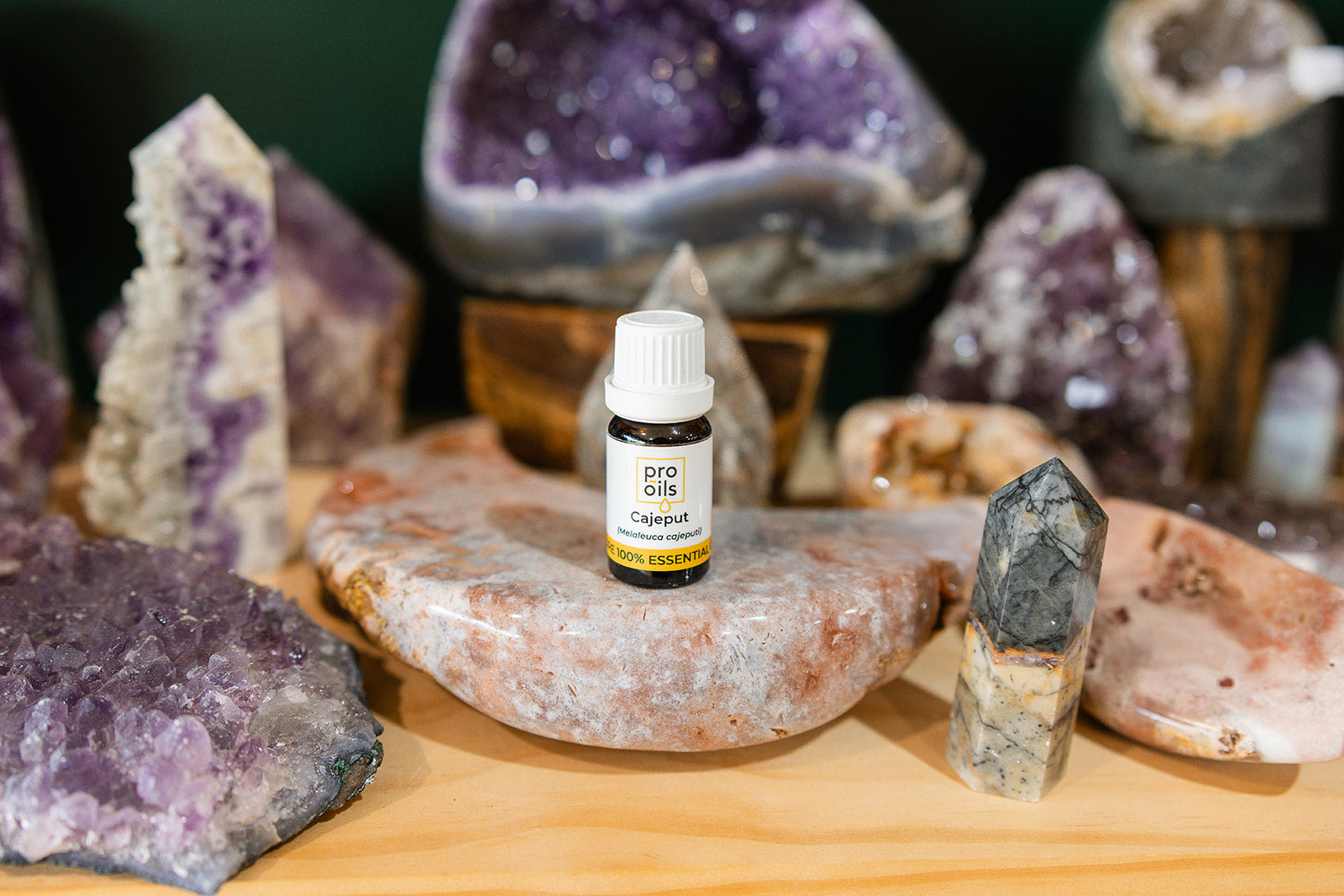 Small bottle of Cedarwood Cajeput Essential Oil on a wooden surface with crystals in the background