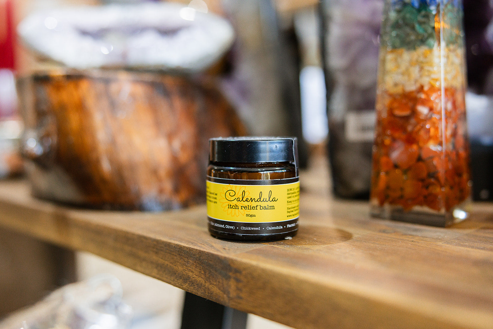 Balms and rubs Calendula Itch Relief displayed on a wooden surface with a blurred background
