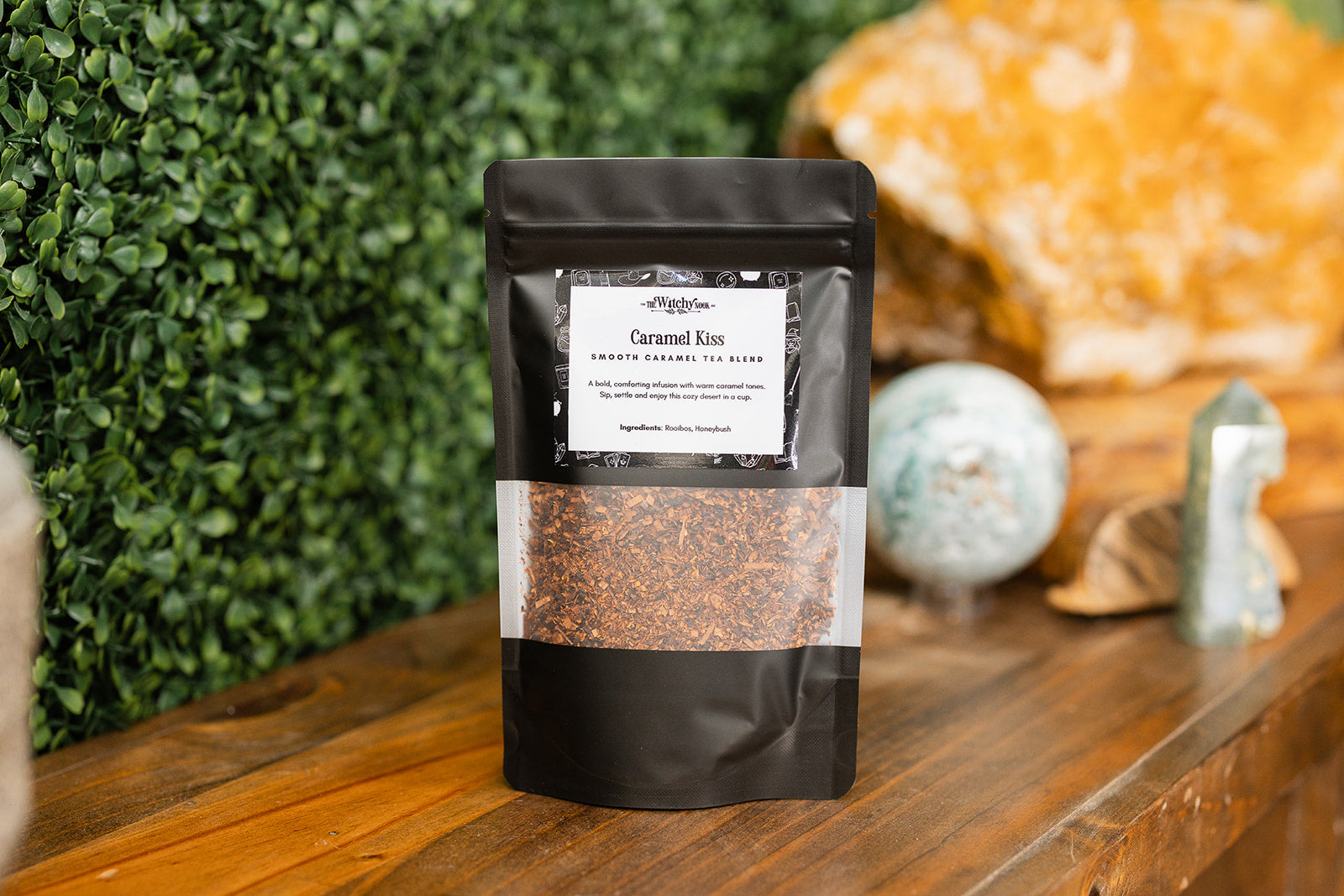 Caramel Kiss Tea Blend displayed on a timber benchtop with a crystal display in the background