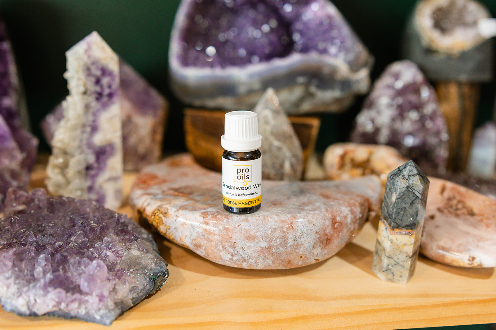 Small bottle of Cedarwood Atlas Essential Oil on a wooden surface with crystals in the background