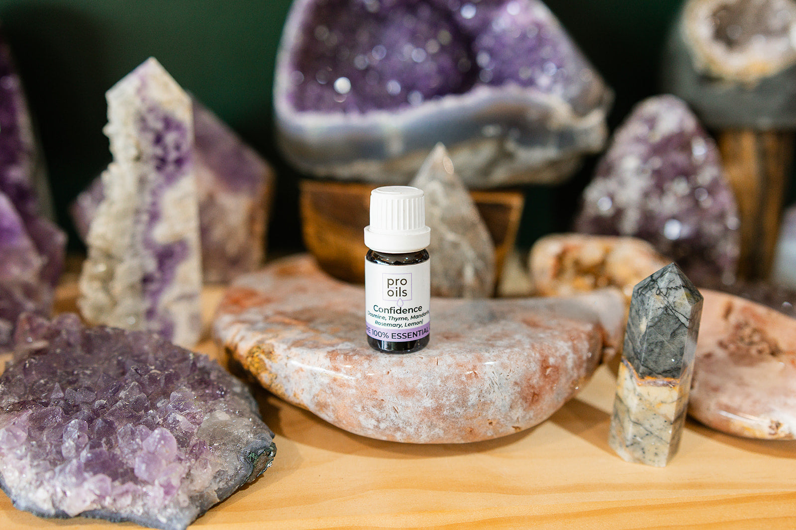 Small bottle of Confidence Essential Oil Blend on a wooden surface with crystals in the background