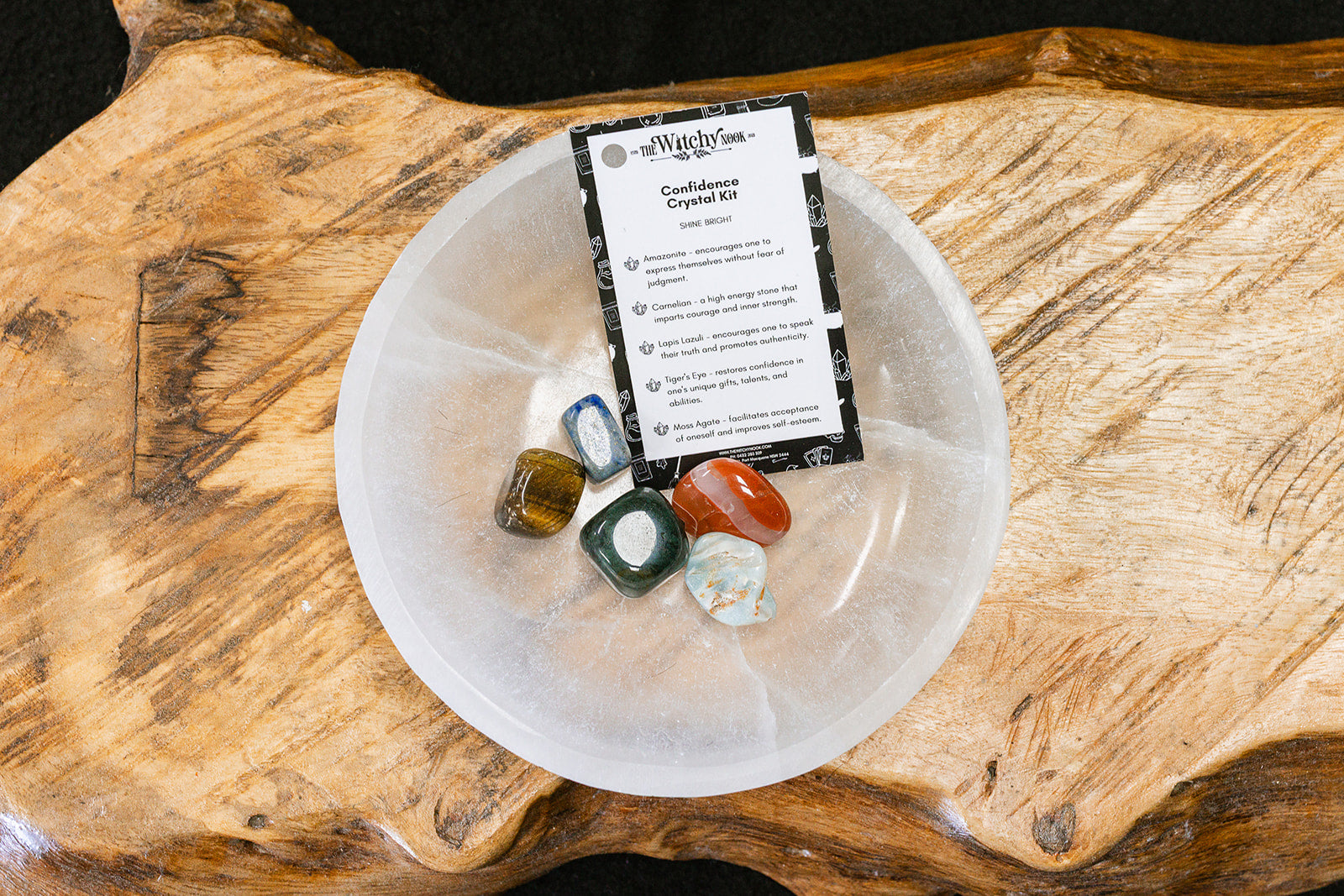 Packaged product labeled 'Confidence Tumble Kit' by 'Witchy Nook' on a wooden surface in the background with products displayed in a bowl.