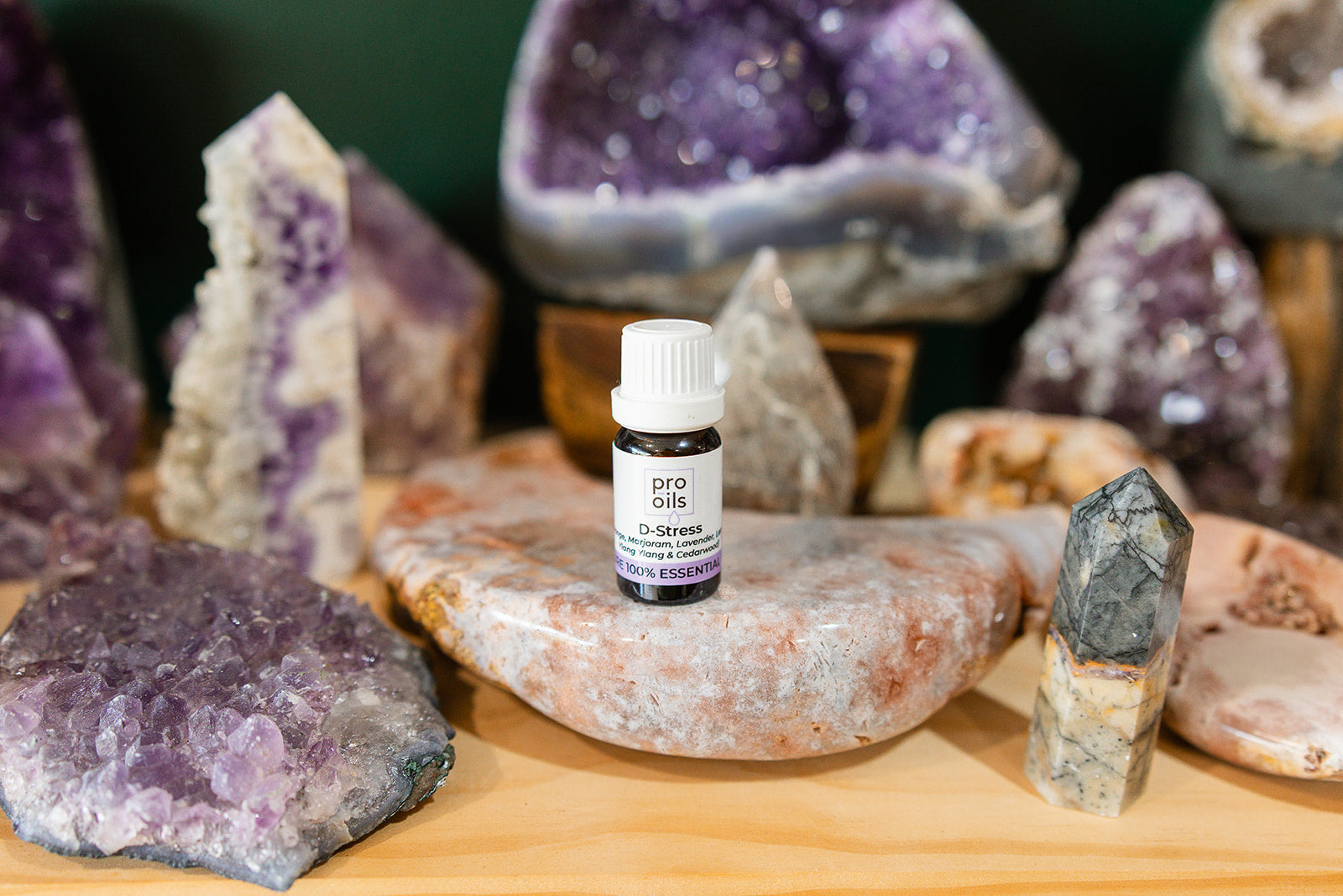 Small bottle of D-Stress Essential Oil Blend on a wooden surface with crystals in the background