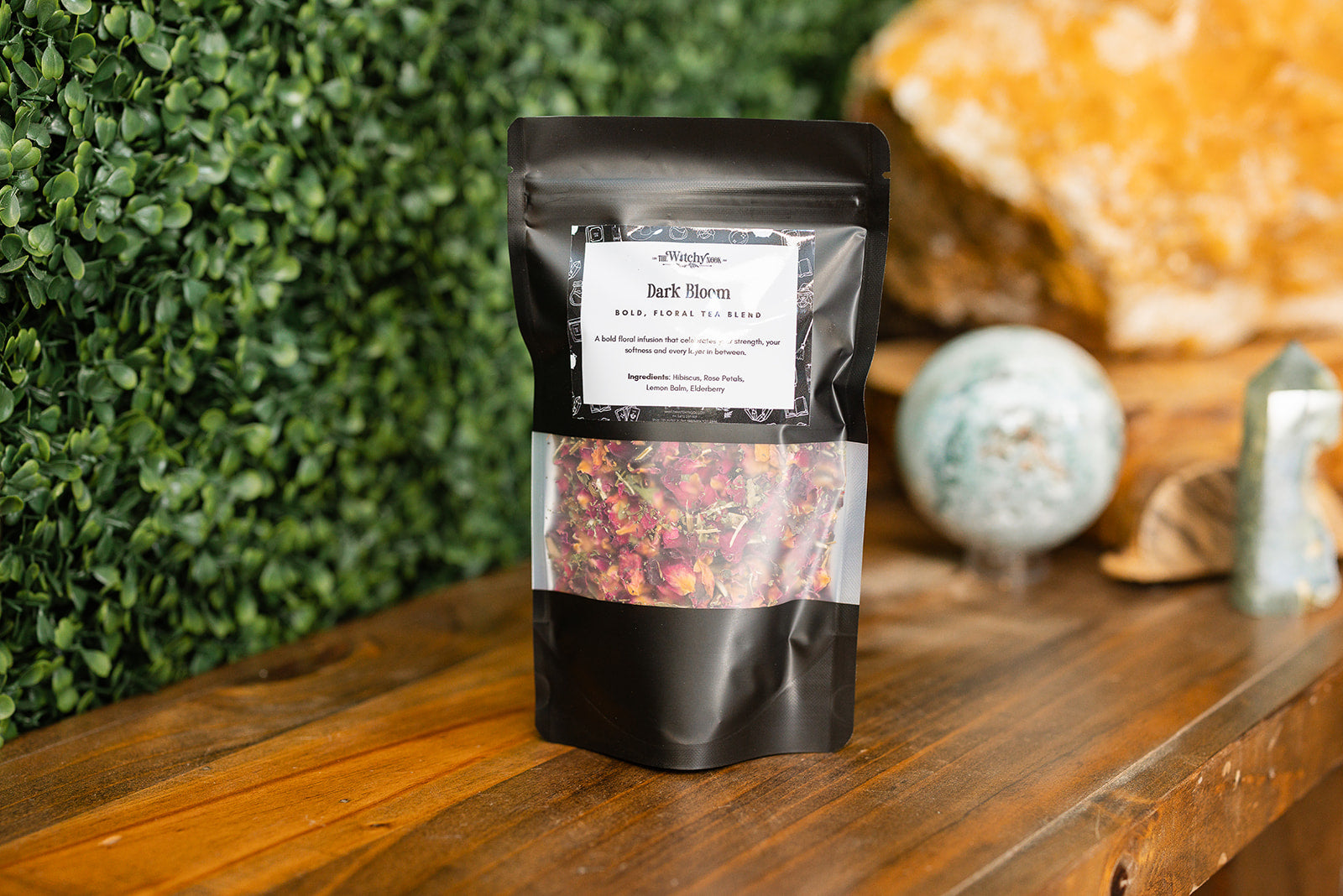 Dark Bloom Tea Blend displayed on a timber benchtop with crystals display in the background