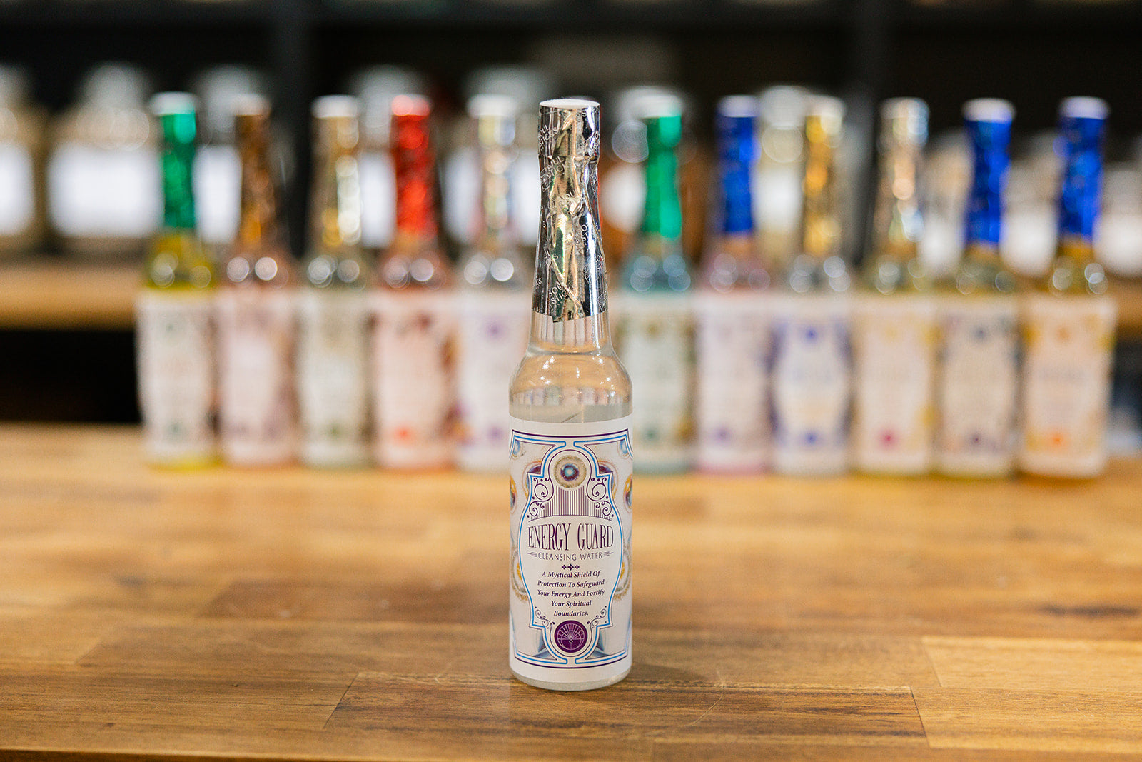 Energy Guard Cleansing Water on a timber background with a collection of cleansing waters displayed in the background