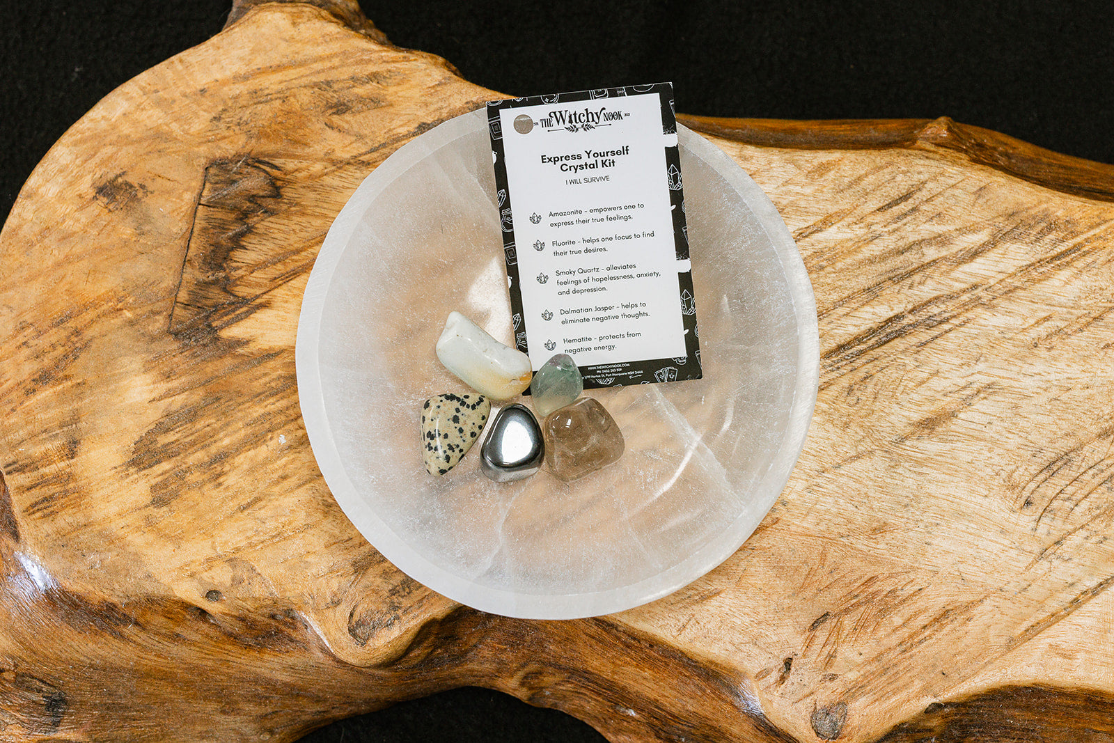 Packaged product labeled 'Express Yourself Tumble Kit' by 'Witchy Nook' on a wooden surface in the background with products displayed in a bowl.