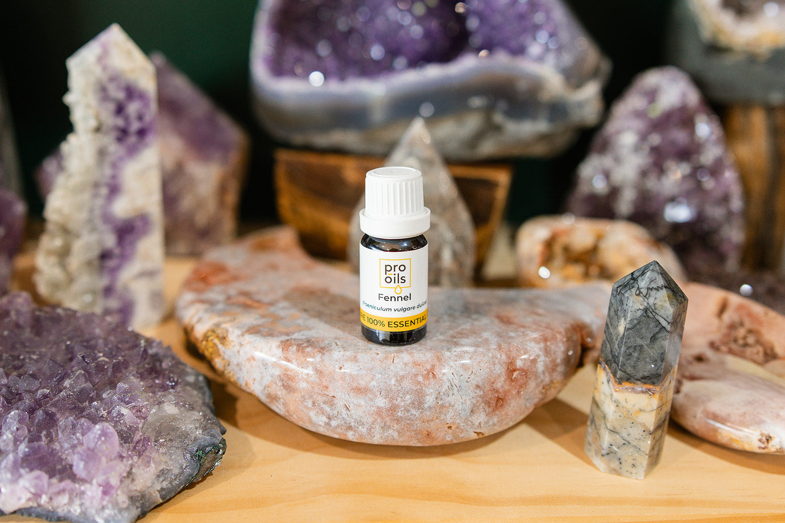 Small bottle of Fennel Essential Oil on a wooden surface with crystals in the background