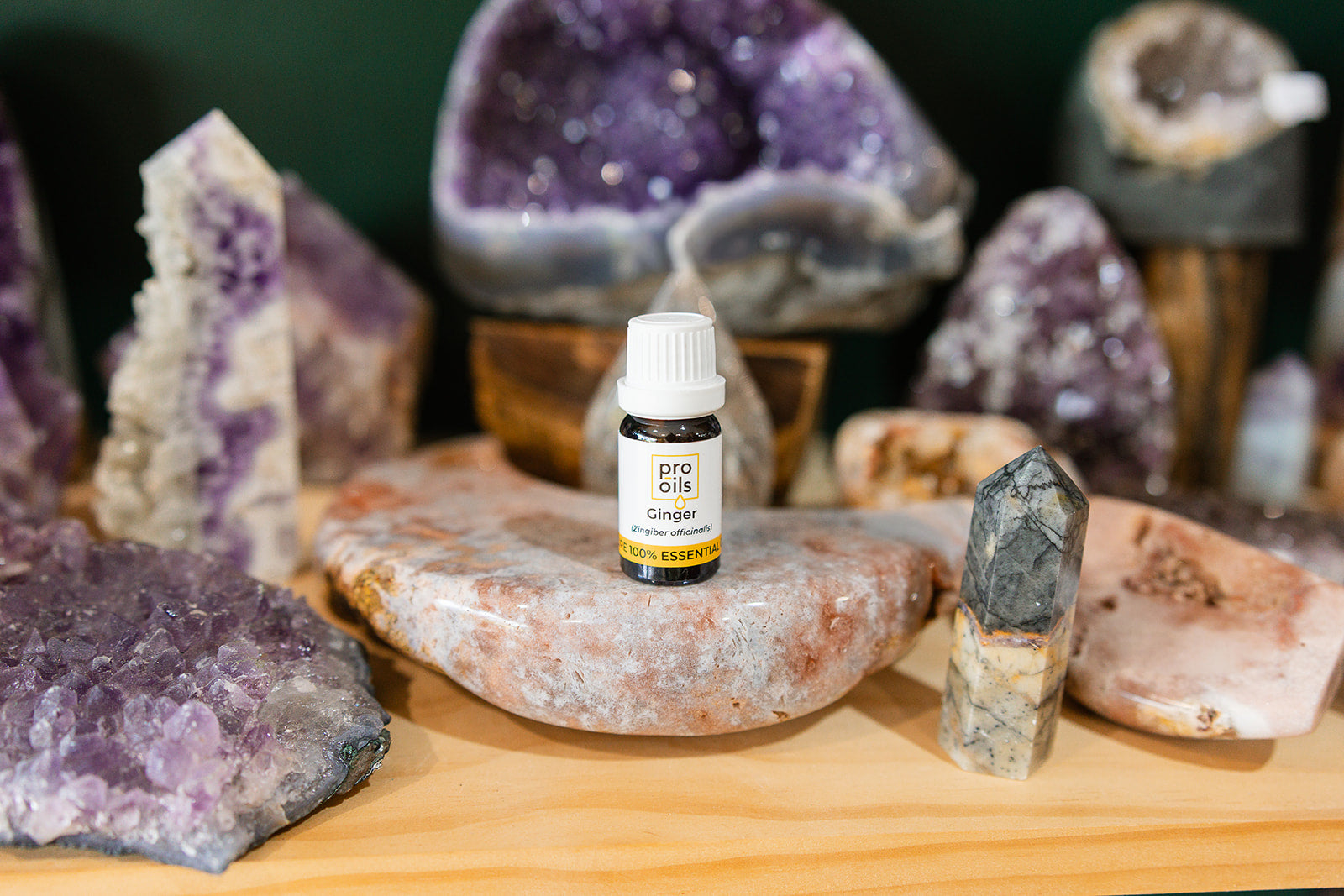 Small bottle of Ginger Fresh Essential Oil on a wooden surface with crystals in the background