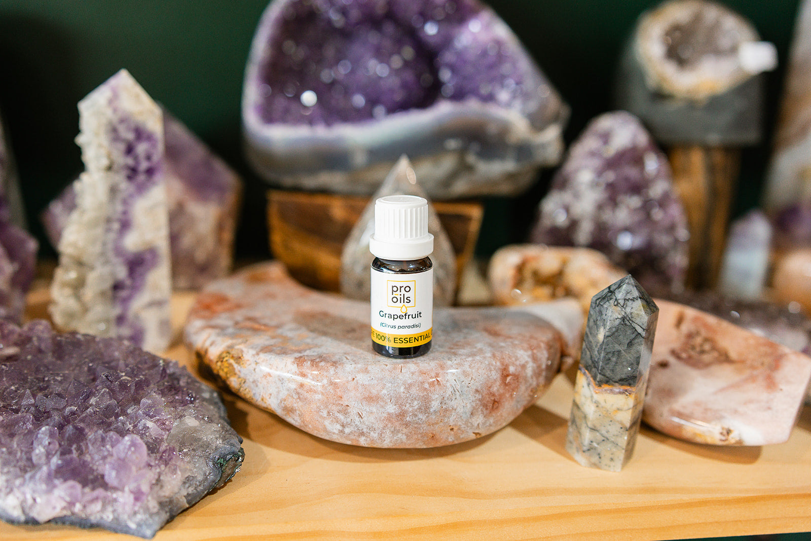 Small bottle of Grapefruit Essential Oil on a wooden surface with crystals in the background