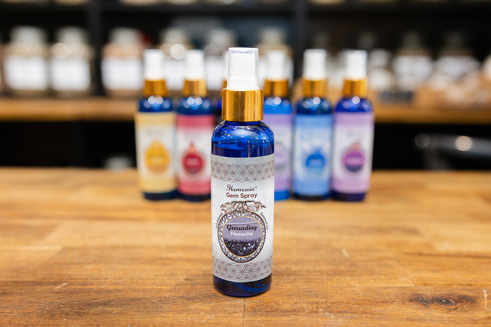 Bottle of Grounding Room Spray displayed in front of a collection on a wooden background