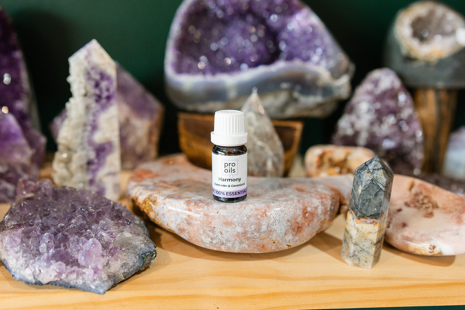 Small bottle of Harmony Essential Oil Blend on a wooden surface with crystals in the background