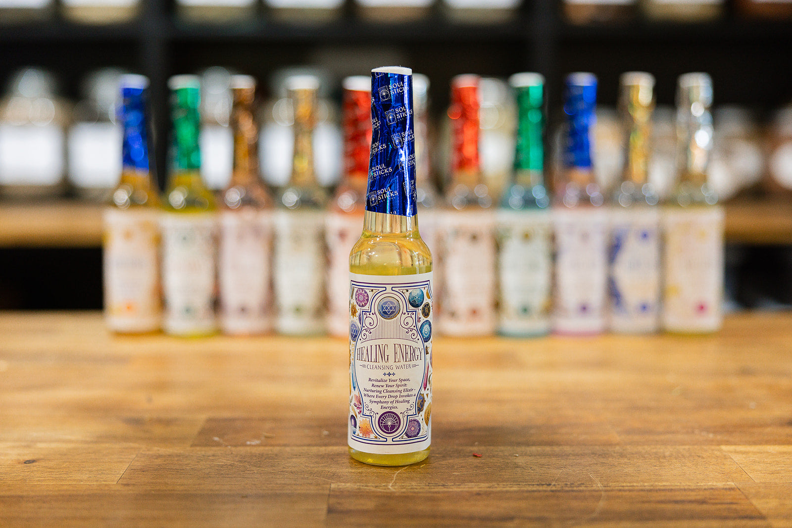 Healing Energy Cleansing Water on a timber background with a collection of cleansing waters displayed in the background