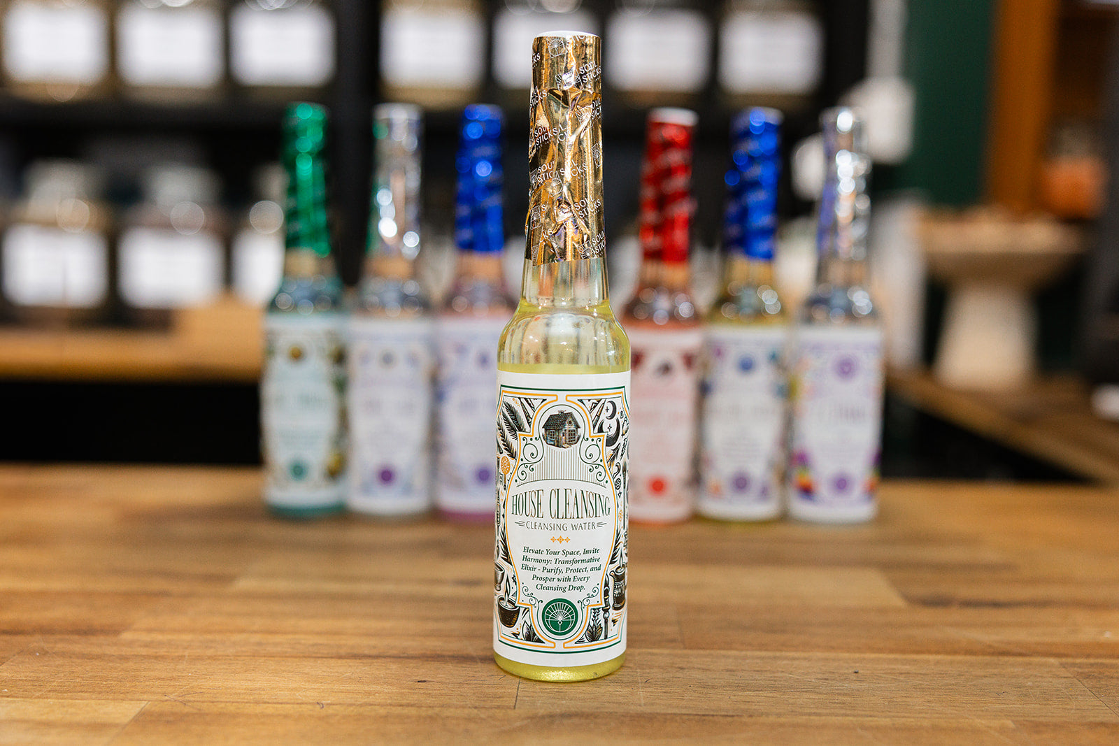 House Cleansing Water on a timber background with a collection of cleansing waters displayed in the background