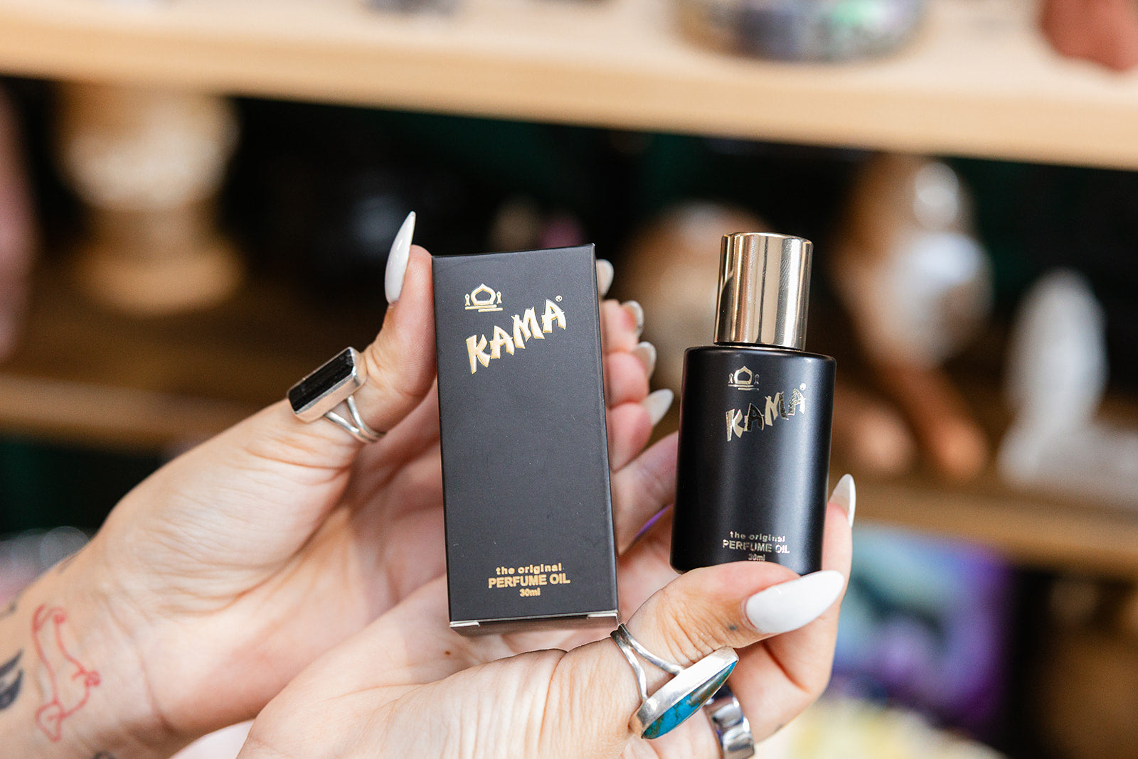 Kama Perfume Oil 30ml product in a persons hand with a blurred background