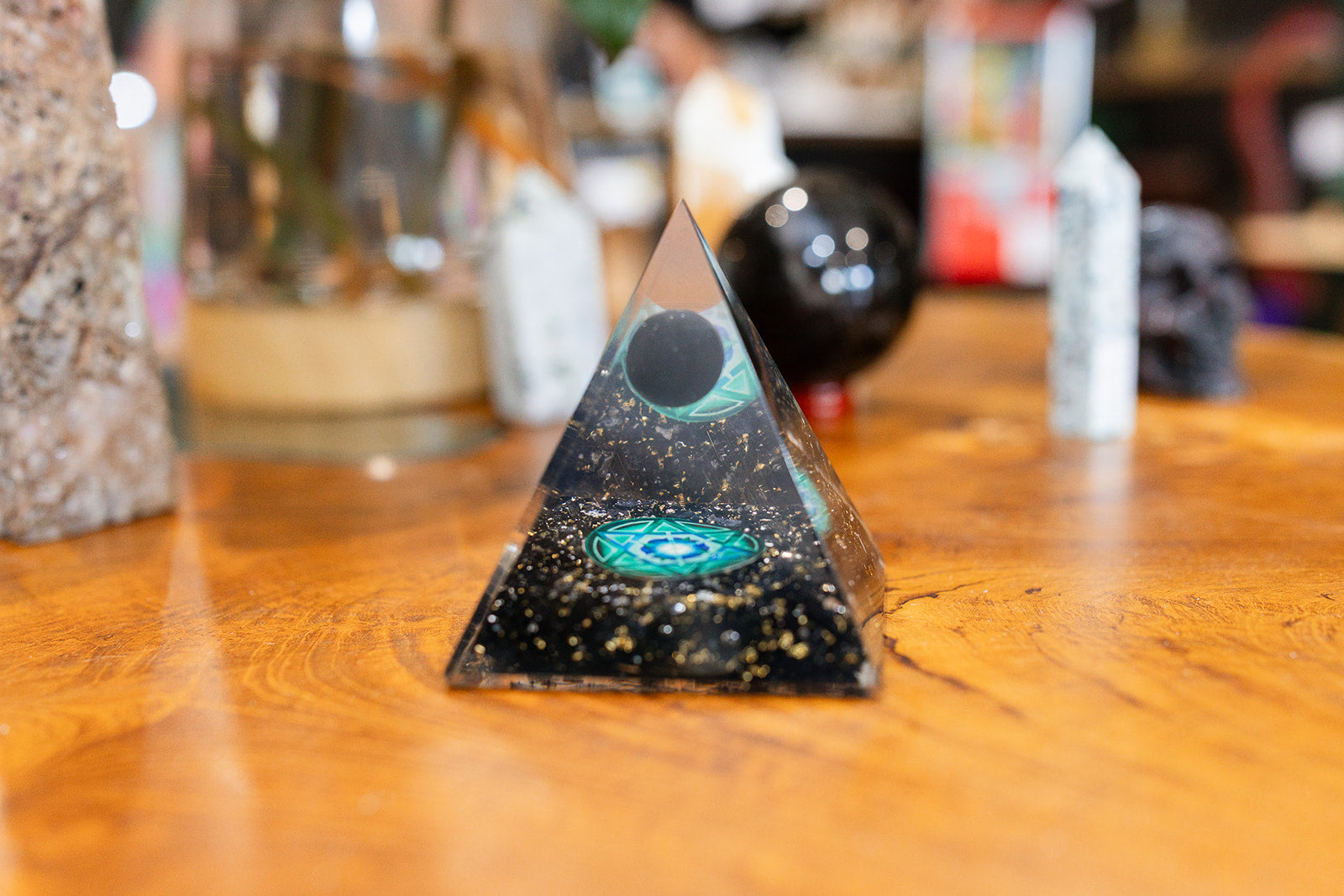 Pyramid-shaped object with a central design on a wooden surface