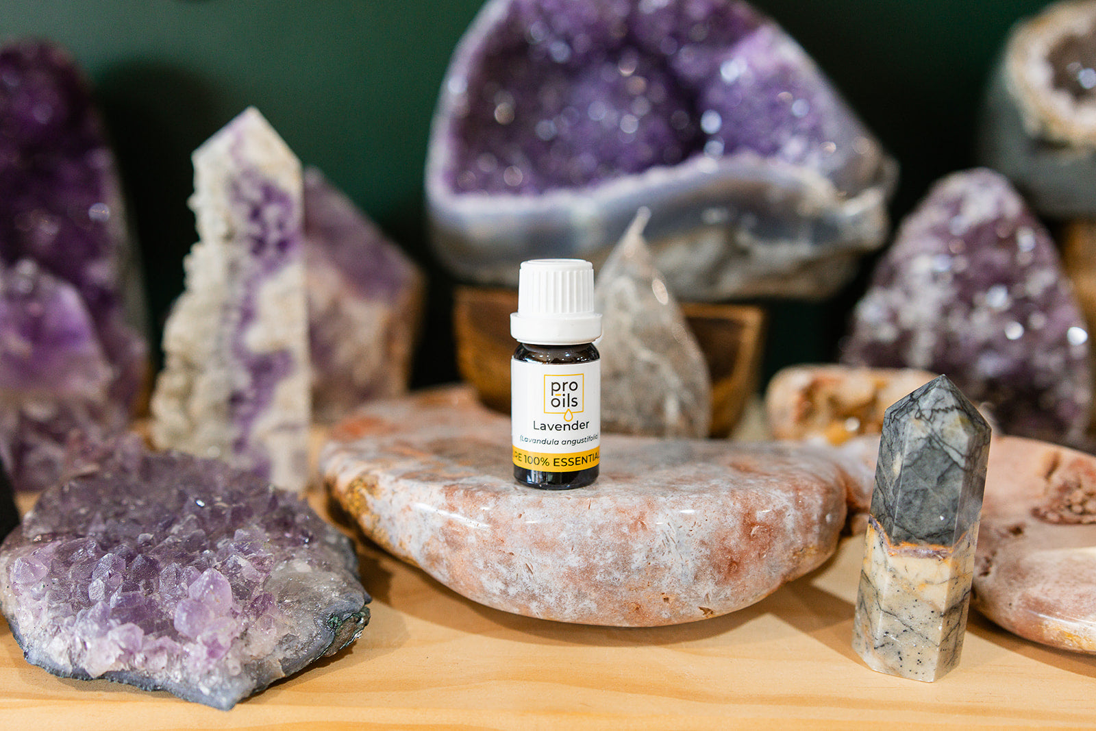 Small bottle of Lavender Essential Oil on a wooden surface with crystals in the background