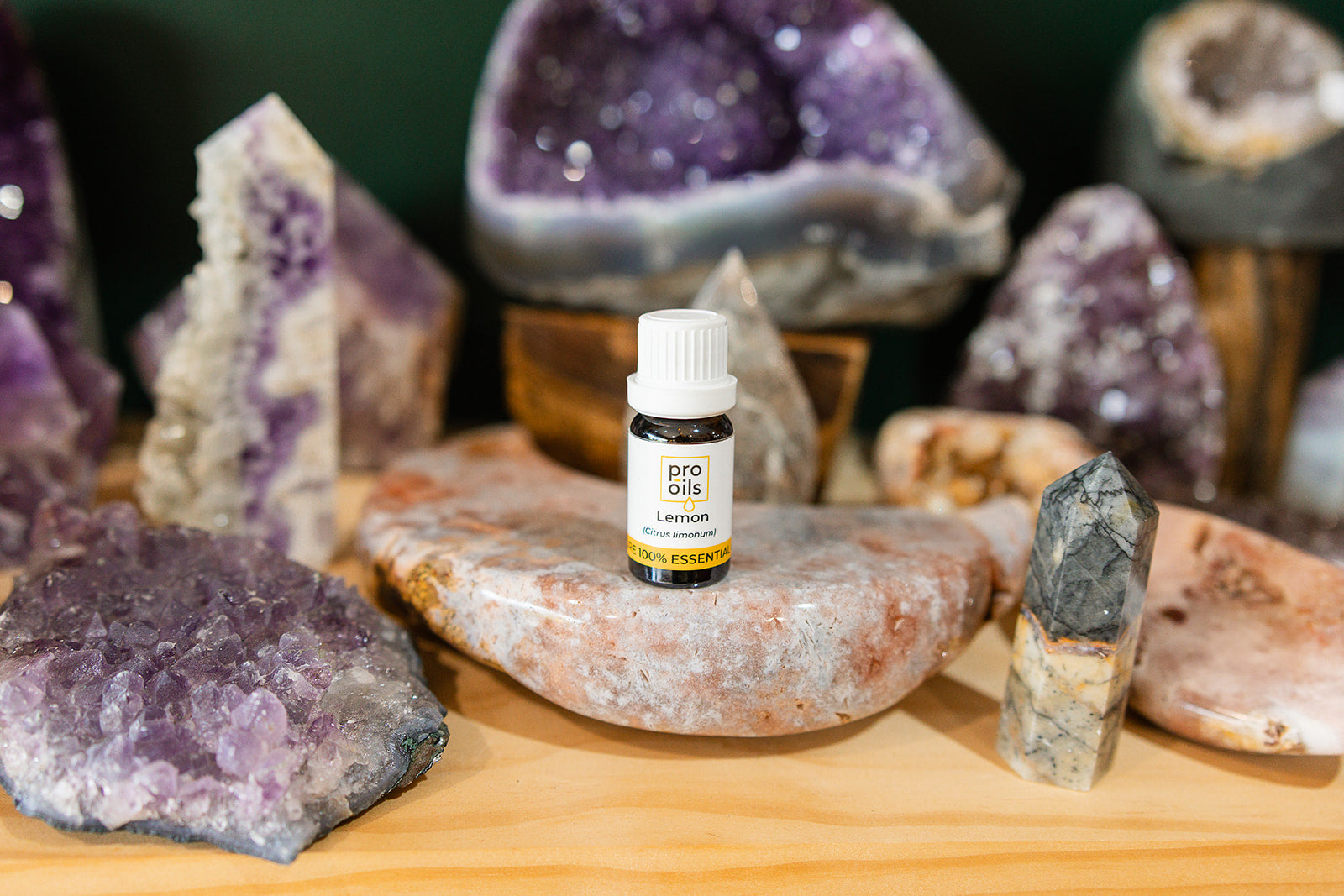 Small bottle of Lemon Essential Oil on a wooden surface with crystals in the background