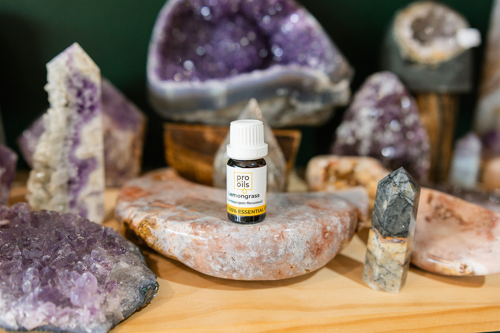 Small bottle of Lemongrass Essential Oil on a wooden surface with crystals in the background
