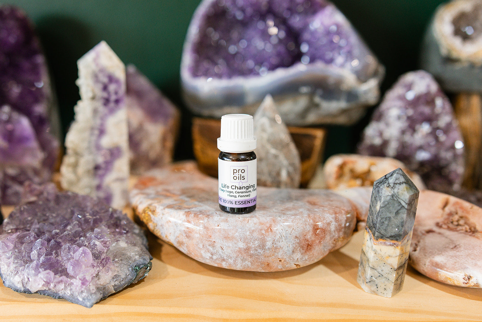 Small bottle of Life-Changing Essential Oil Blend on a wooden surface with crystals in the background