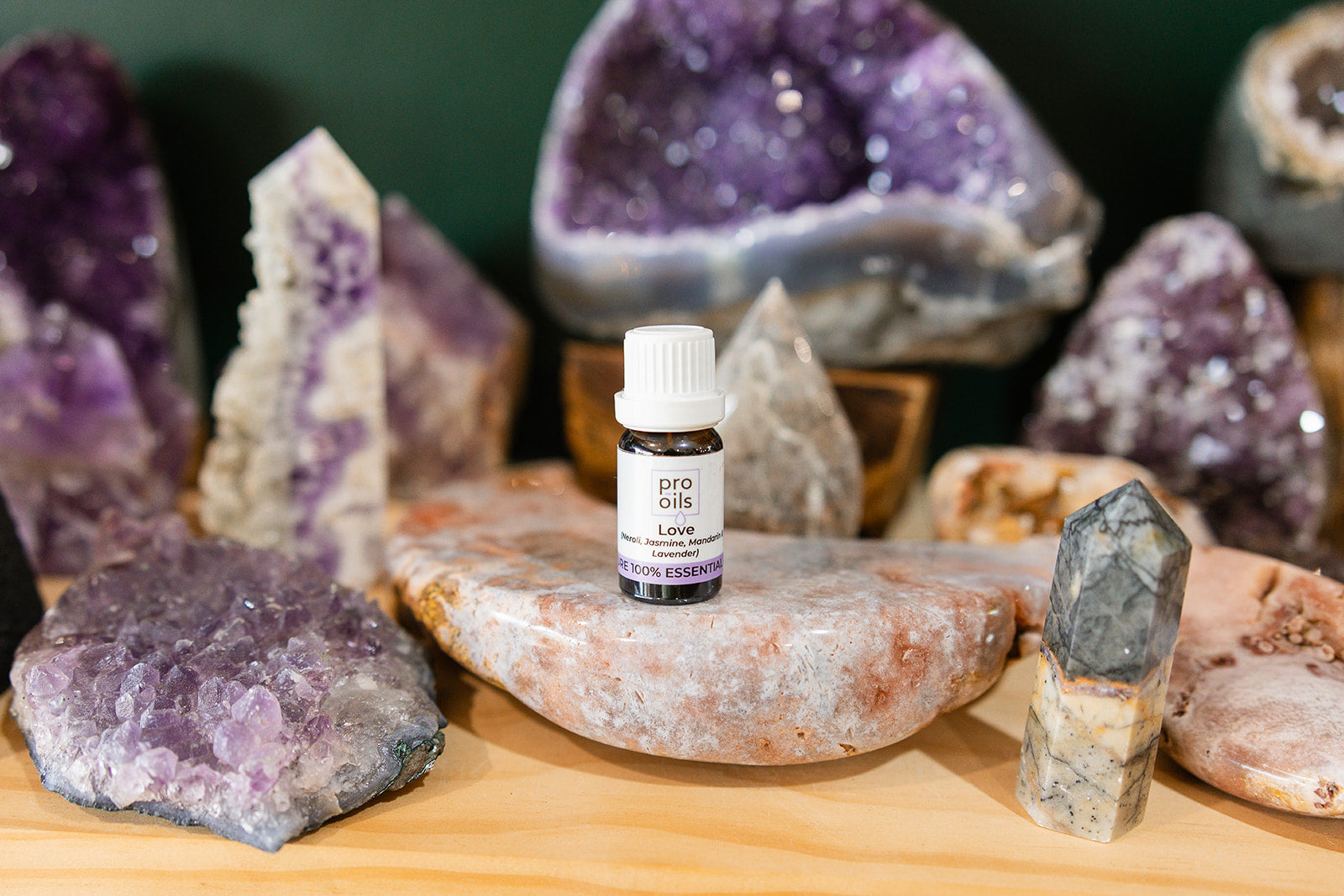 Small bottle of Love Essential Oil Blend on a wooden surface with crystals in the background