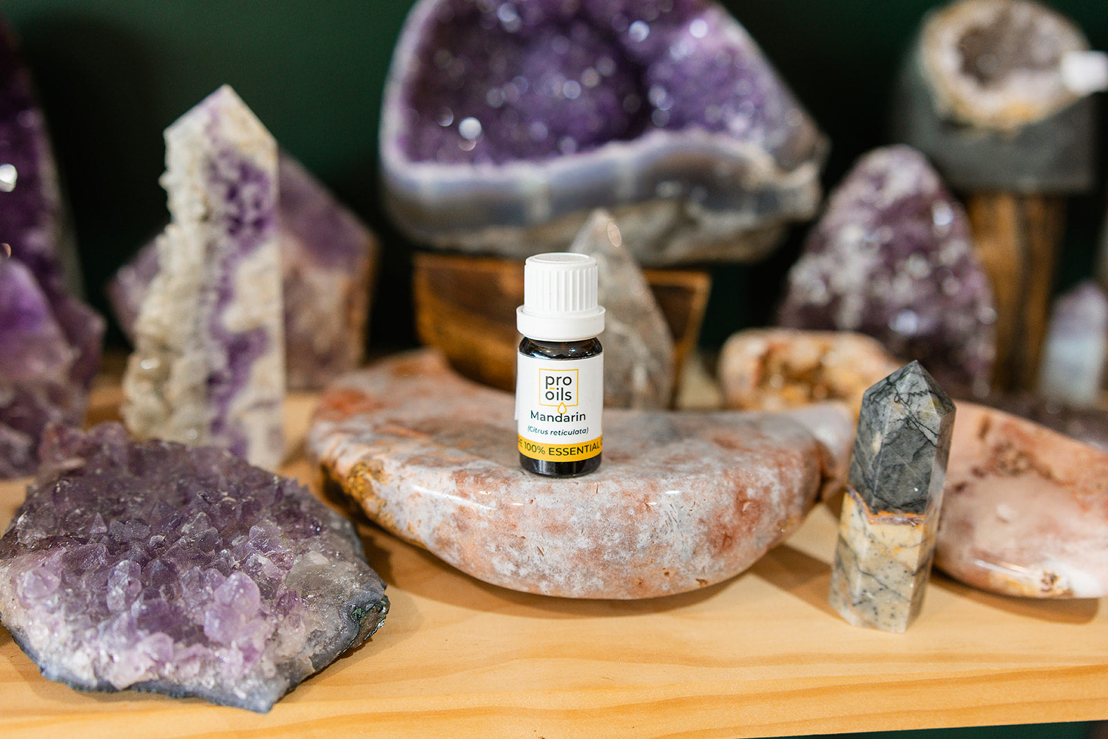 Small bottle of Mandarin Essential Oil on a wooden surface with crystals in the background