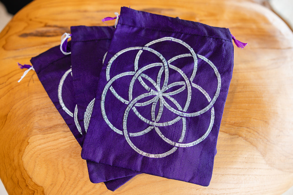 Velvet Tarot card bags with "Flower of life" sacred geometry design on wooden background