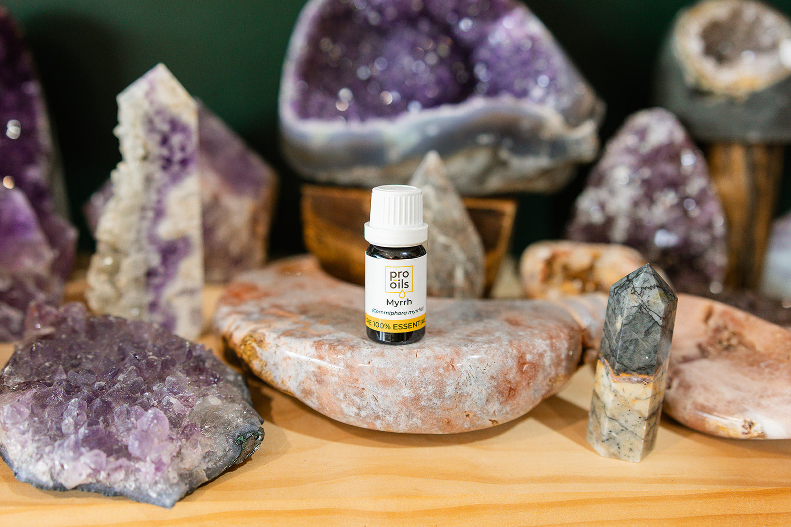 Small bottle of Myrrh Essential Oil on a wooden surface with crystals in the background