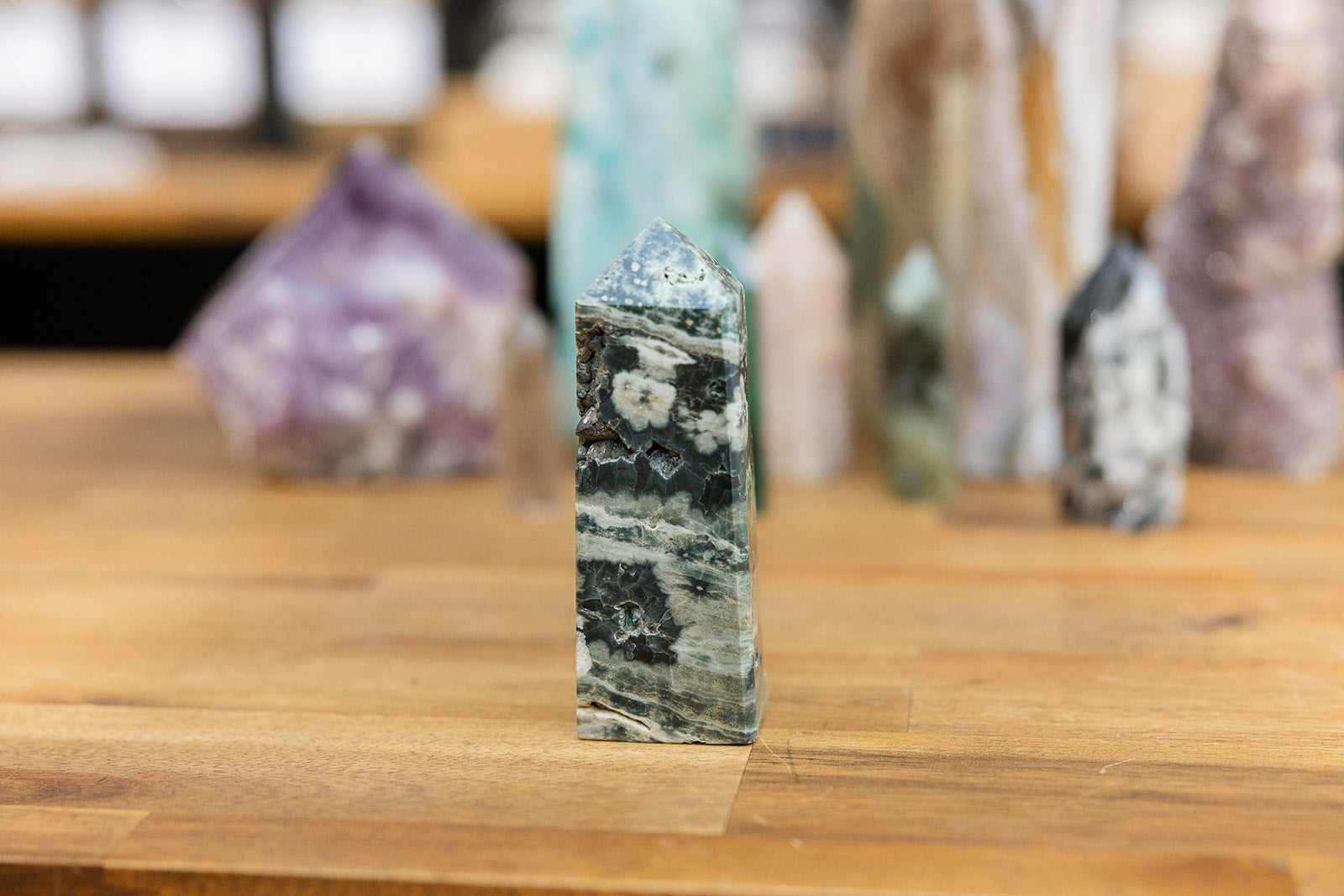 Natural crystal Ocean Jasper Tower with a collection of colourful towers on wooden background