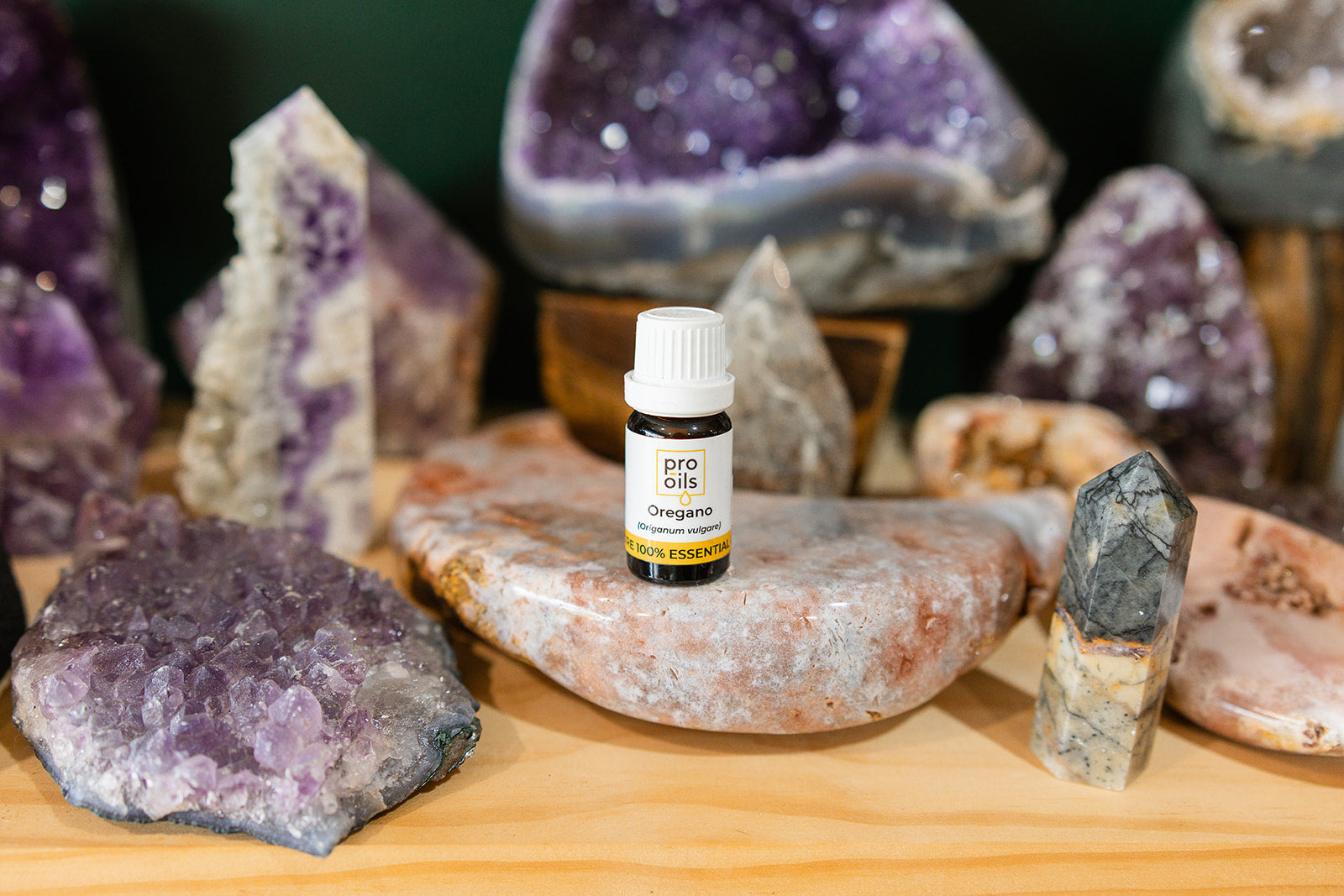 Small bottle of Oregano Essential Oil on a wooden surface with crystals in the background