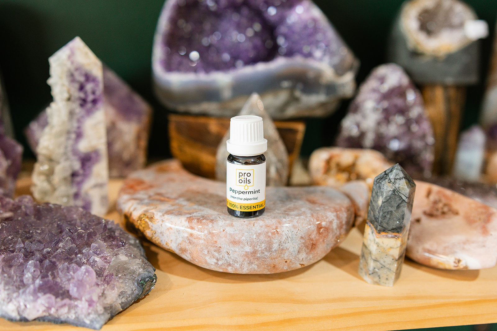 Small bottle of Peppermint Essential Oil on a wooden surface with crystals in the background