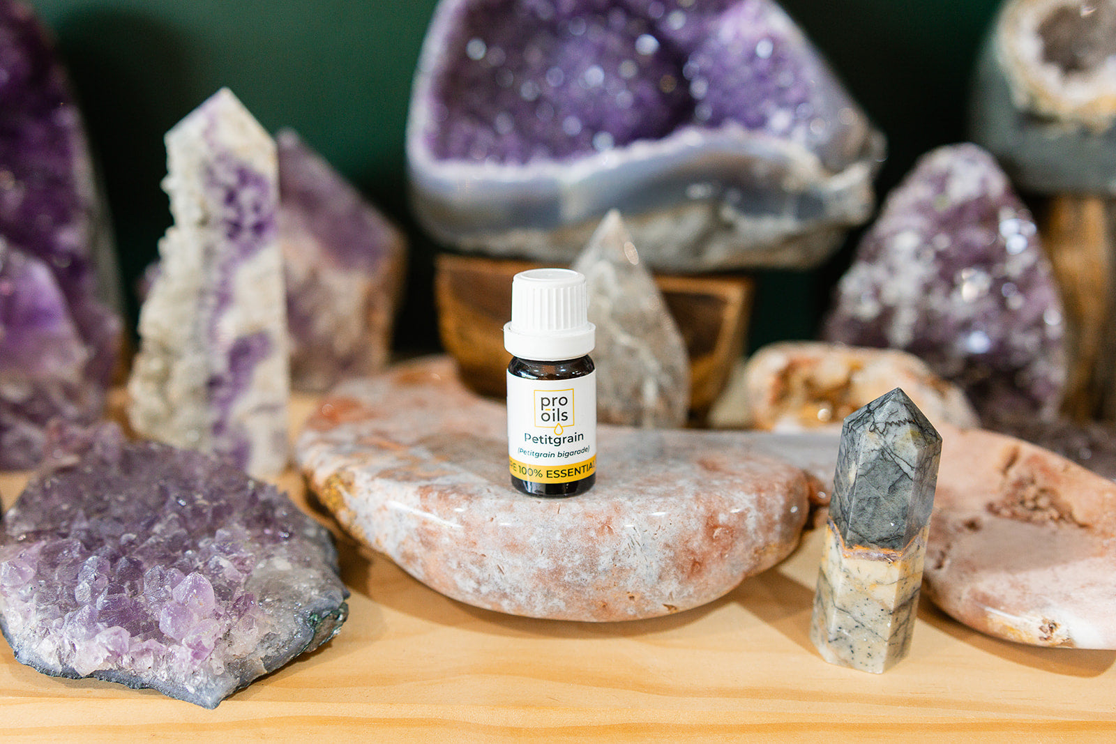 Small bottle of Petitgrain Essential Oil on a wooden surface with crystals in the background