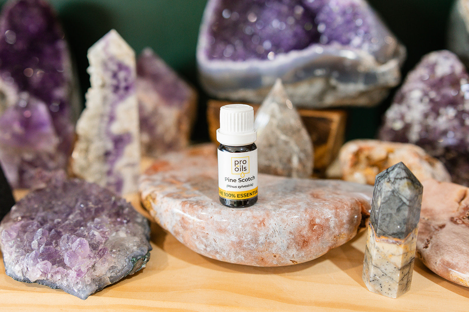 Small bottle of Pine Scotch Essential Oil on a wooden surface with crystals in the background