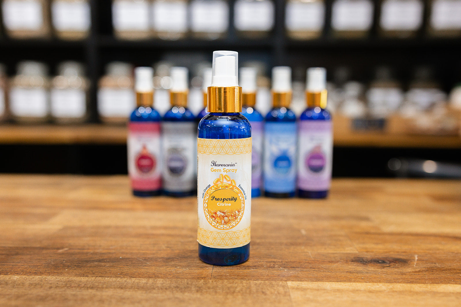 Bottle of Prosperity room spray displayed with collection of mixed room sprays on wooden background