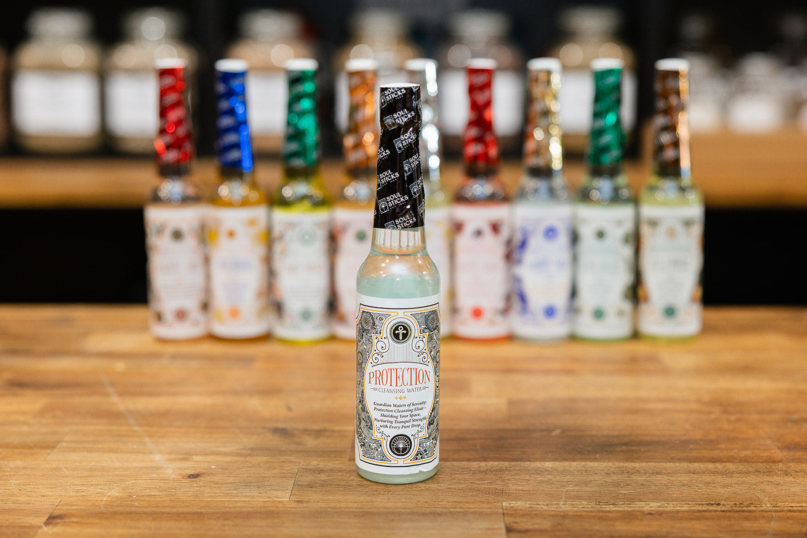 Bottle of Protection Cleansing Water displayed with collection of mixed cleansing waters on wooden background 