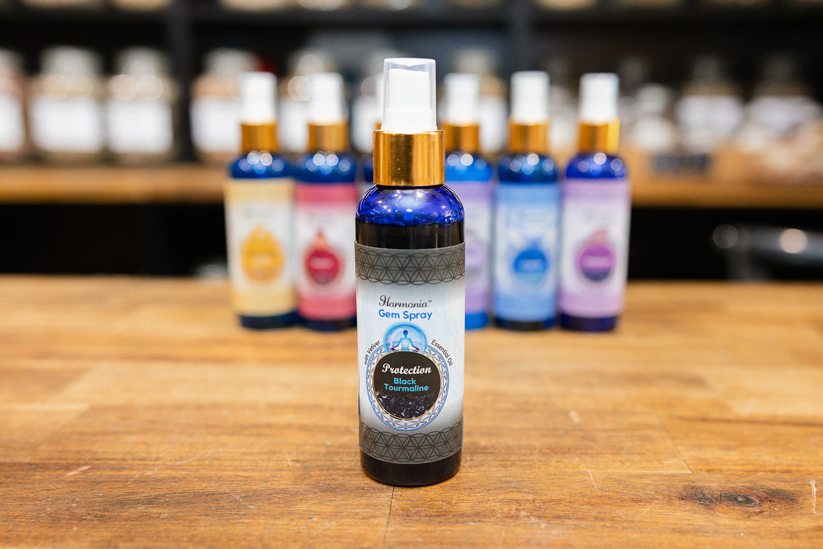 Bottle of Protection room spray displayed with collection of mixed room sprays on wooden background