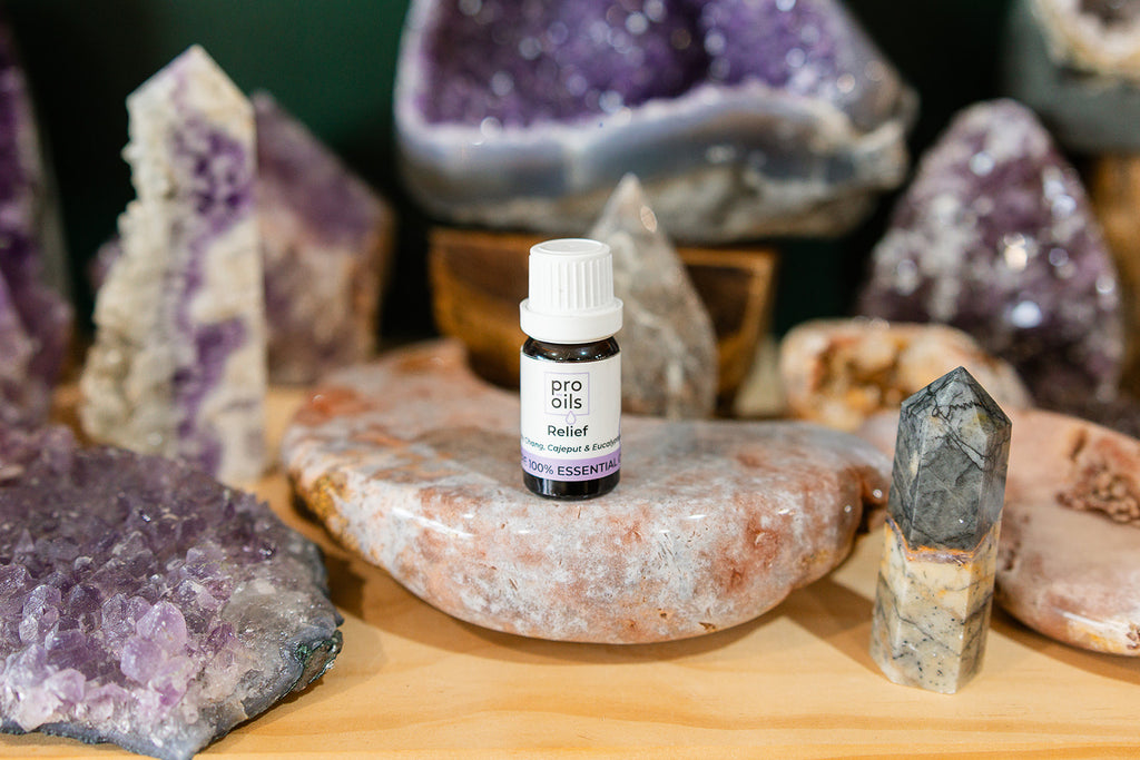 Small bottle of Relief Essential Oil Blend on a wooden surface with crystals in the background