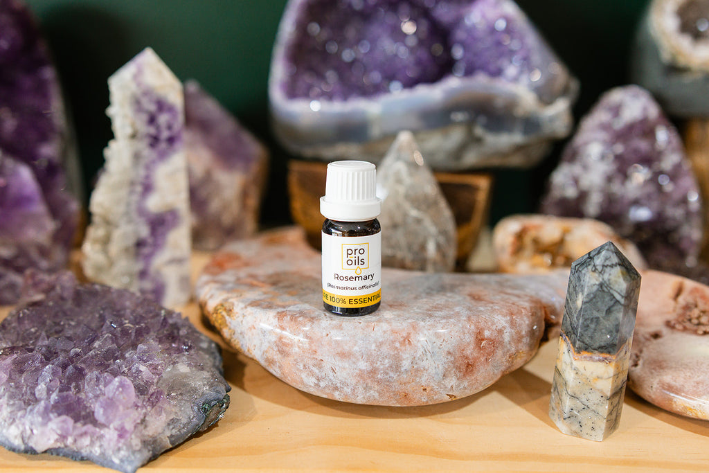 Small bottle of Rosemary Essential Oil on a wooden surface with crystals in the background