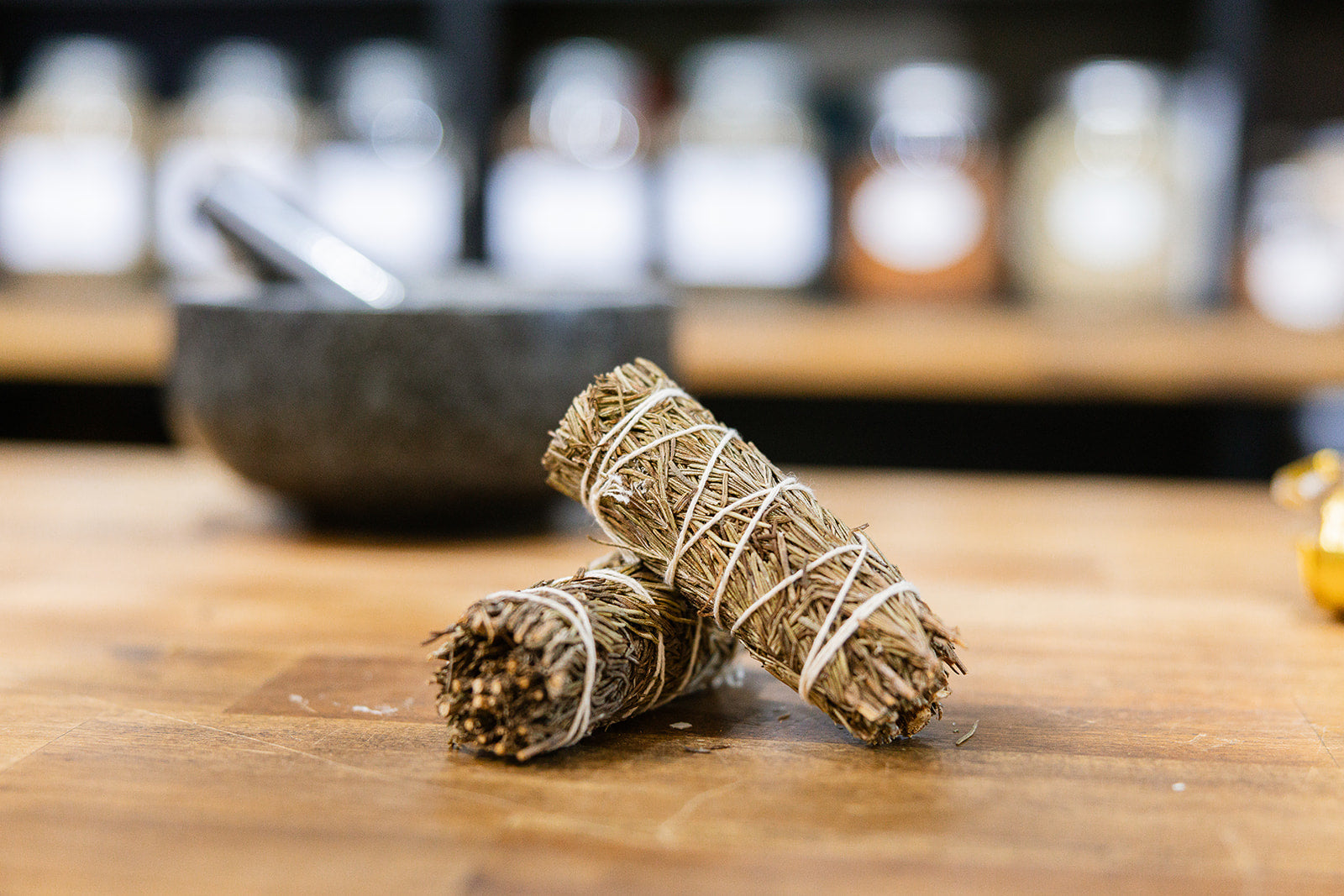Rosemary smudge sticks on a timber bench with a mortar and pestle in background