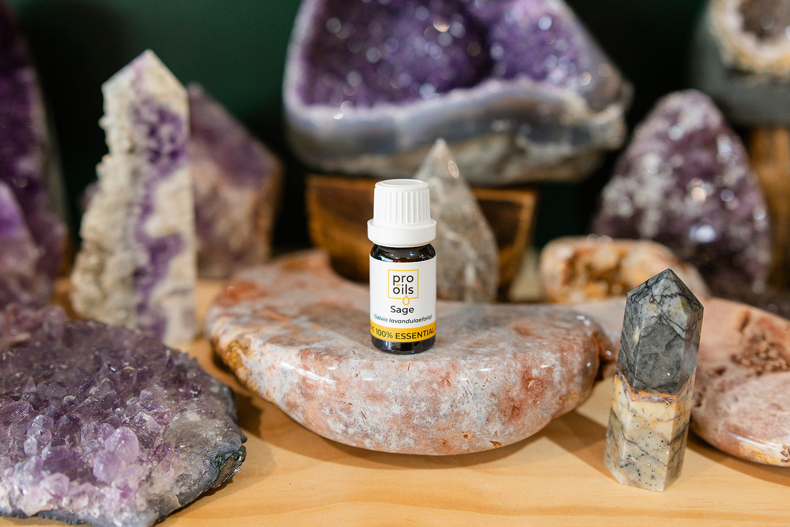 Small bottle of Sage Dalmatian Essential Oil on a wooden surface with crystals in the background