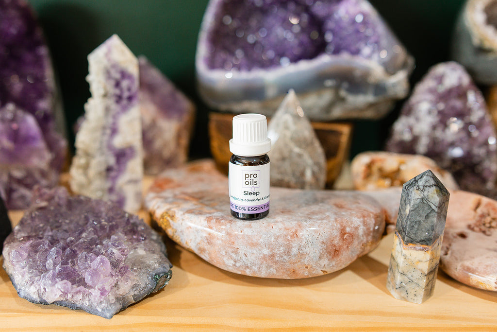 Small bottle of Sleep Essential Oil Blend on a wooden surface with crystals in the background