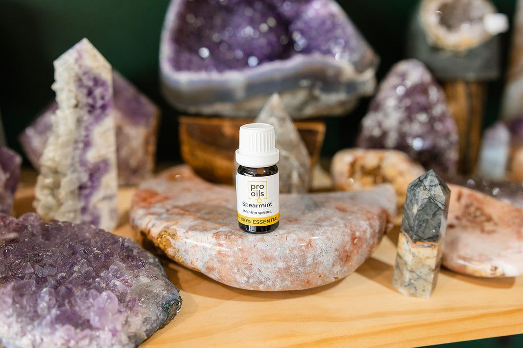Small bottle of Spearmint Essential Oil on a wooden surface with crystals in the background