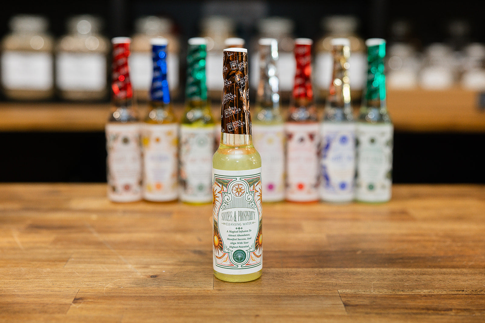 Bottle of Success and Prosperity Cleansing Water with collection displayed on wooden background