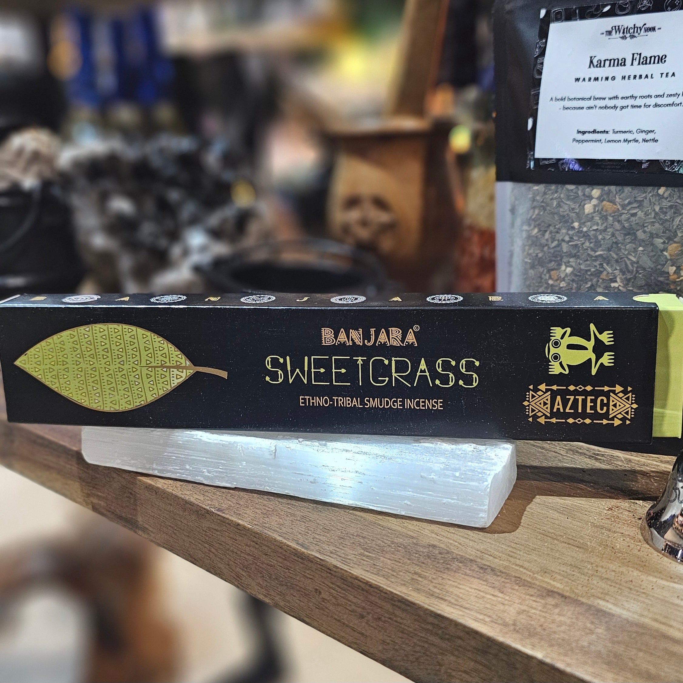 ‘Banjara Sweetgrass Incense’ Displayed on a wooden table surrounded by crystals and herbs. 